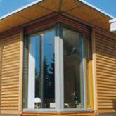 Moderne Holzfassade mit großen Fenstern für nachhaltiges Wohnen.
