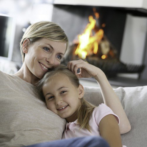 Gemütliche Familie beim Entspannen vor dem Kamin zu Hause.