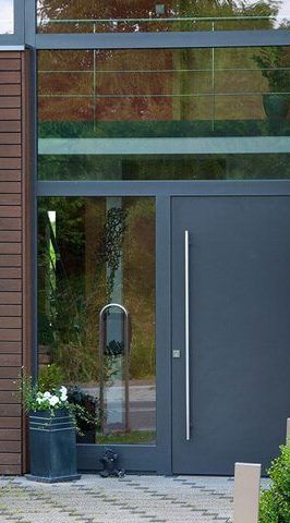Hauseingang mit moderner Glasfassade und eleganter Tür in dunklem Grau.