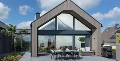 Modernes Haus mit großen Glasflächen und Holzfassade, ideal für nachhaltiges Wohnen.