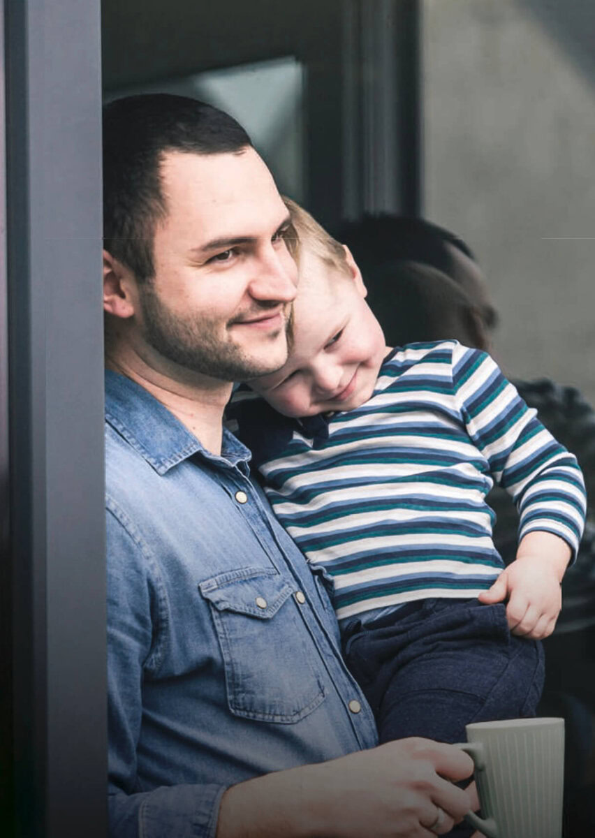 Vater mit Kind beim Blick nach draußen, entspannte Atmosphäre, Familienmoment.