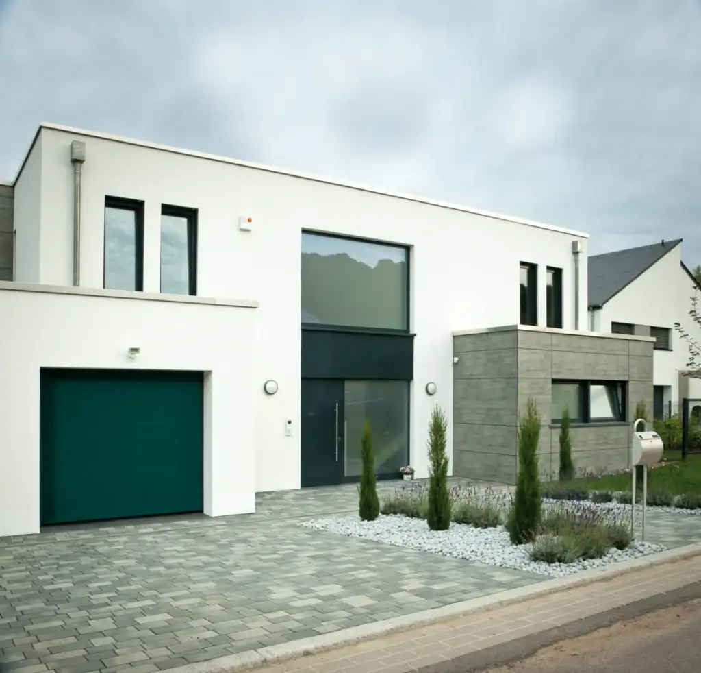 Moderne weiße Neubau-Villa mit Graufasade und gepflegtem Vorgarten, elegante Hausgestaltung, ideal für nachhaltiges Wohnen.
