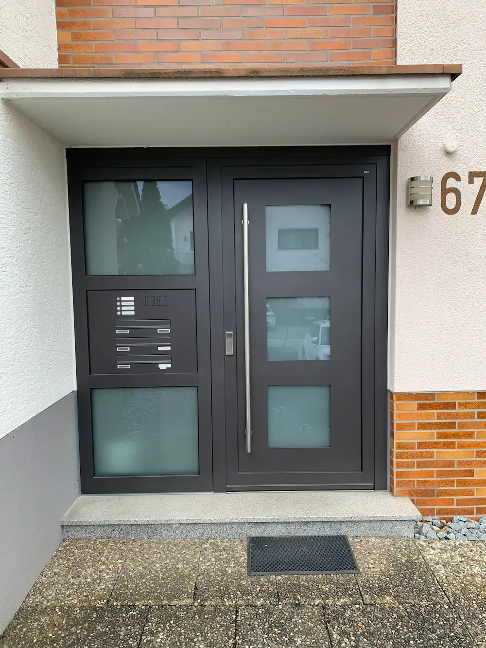 Ein moderner Hauseingang mit schwarzen Türen und Glasfenstern in einer stilvollen Wohnanlage.