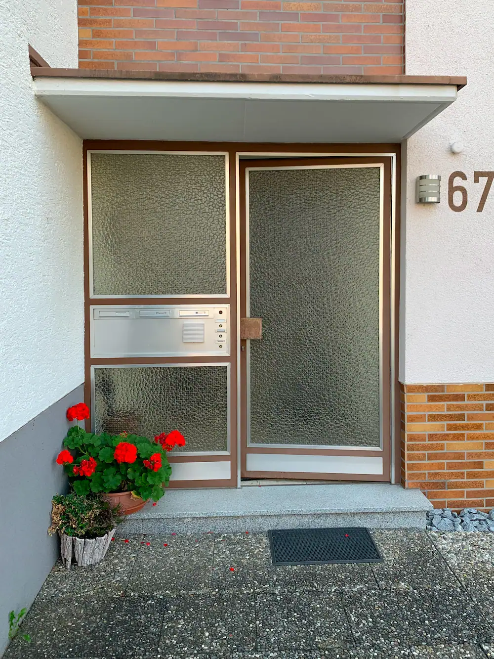 1. Hochwertige Kunststoff-Glas-Tür mit Briefkasten und Blumentopf, barrierefrei.