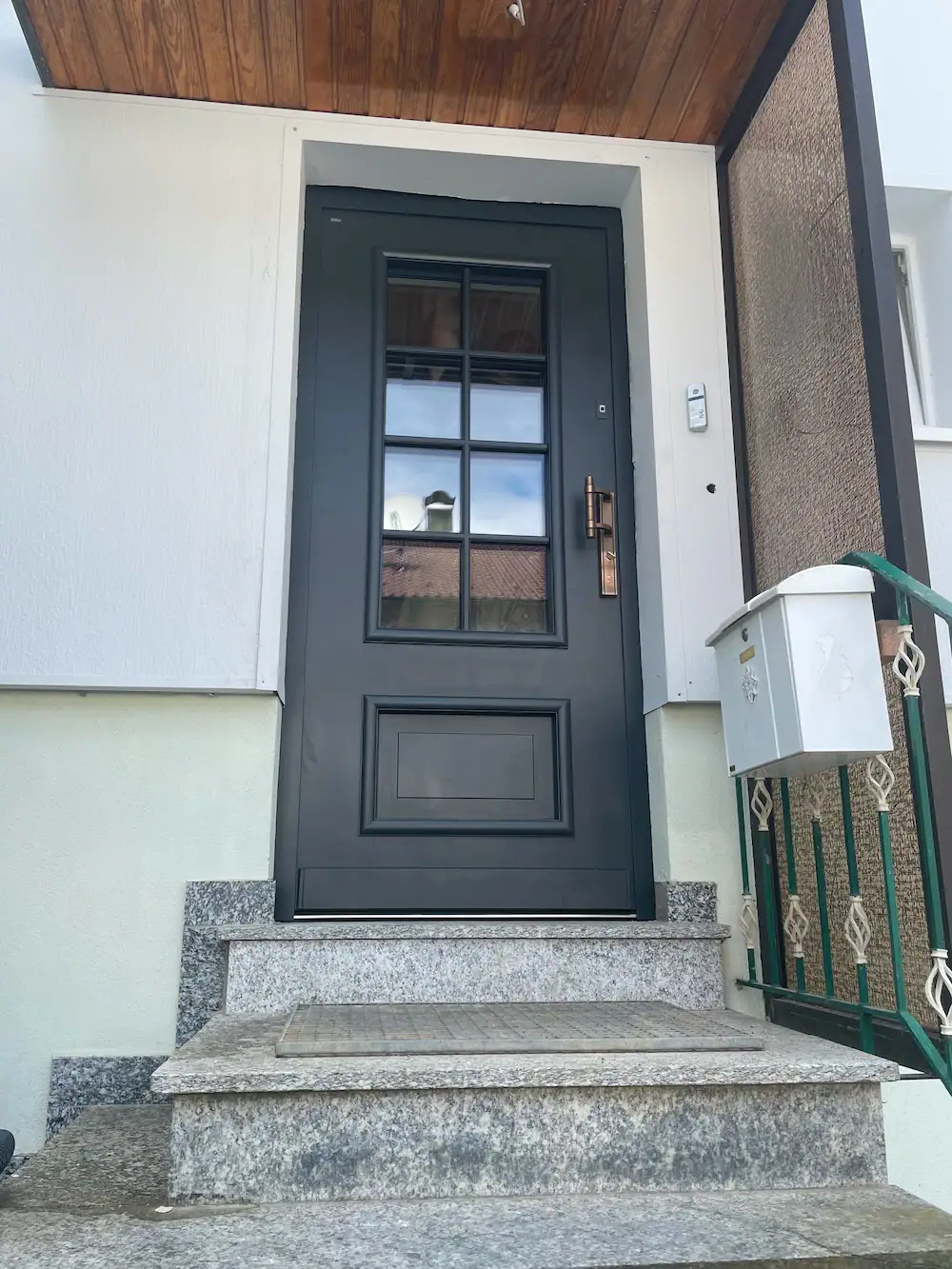 Elegante Eingangstür in Schwarz mit Glasfenstern, moderner Haustürdesign, barrierefreier Zugang, hochwertige Materialqualität.