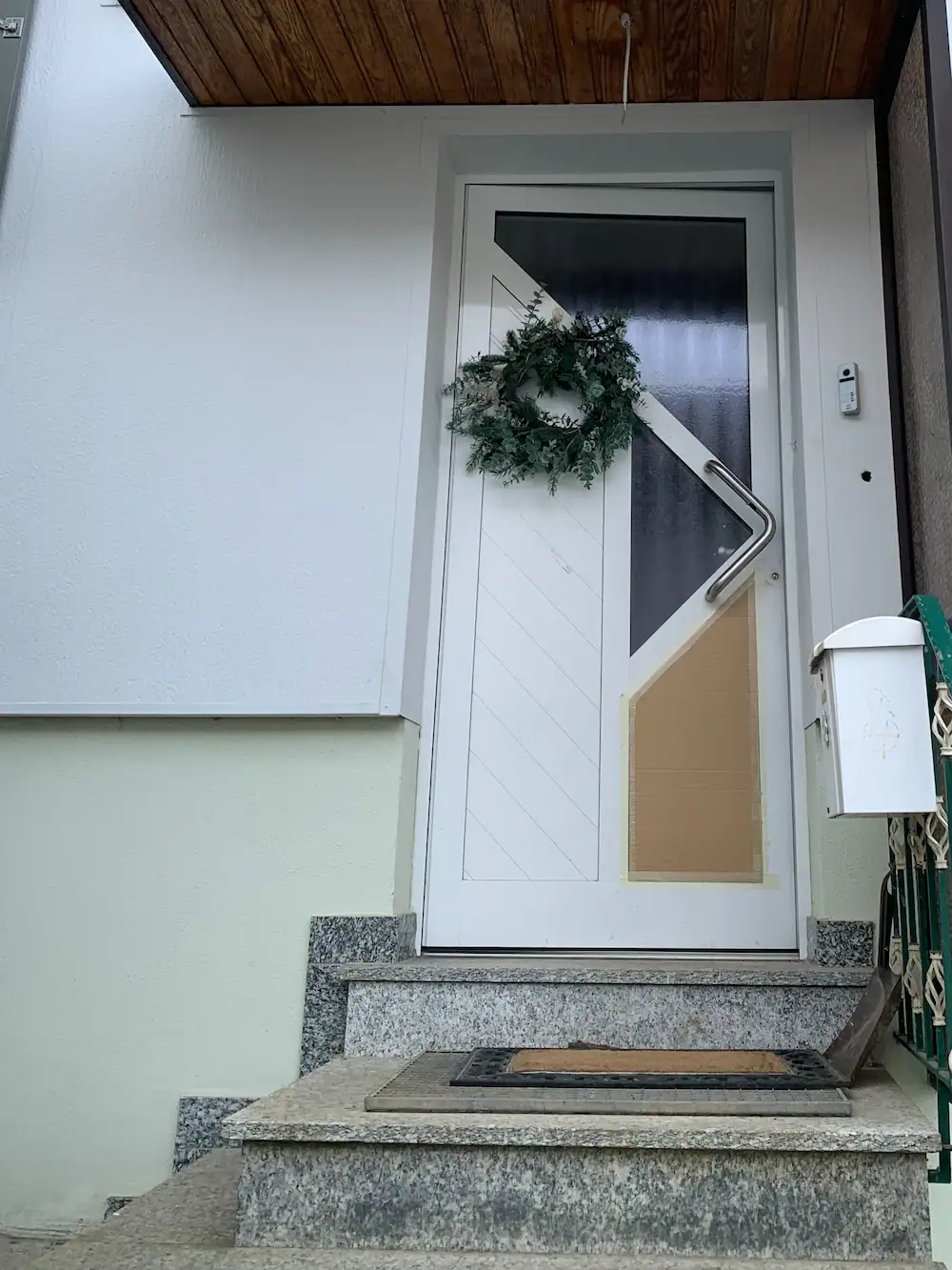 Stabile Haustür mit dekorativem Kranz, hochwertig gestaltete Eingangszone.