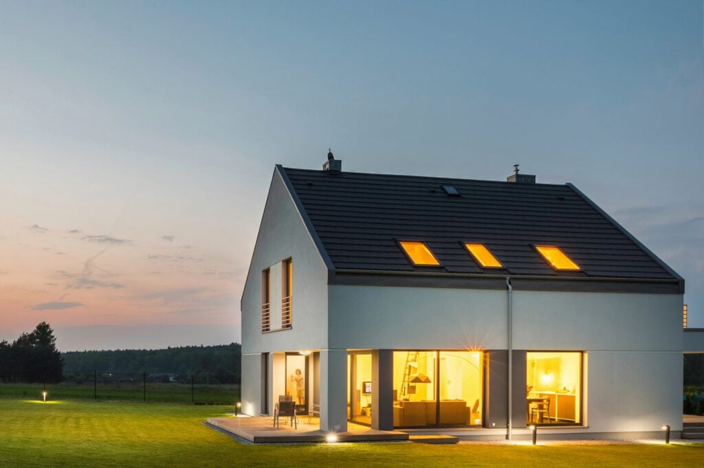 Moderne, energieeffiziente Haus mit großem Garten bei Sonnenuntergang.
