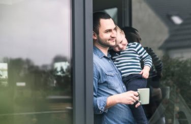 Stolzer Vater mit Kind schaut aus dem Fenster, entspannt und glücklich, Familienzeit in entspannter Atmosphäre.