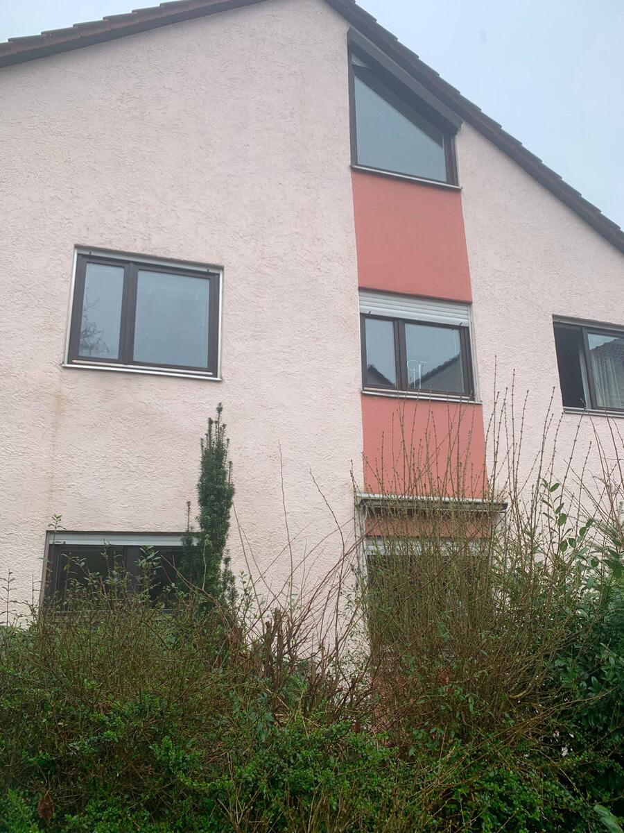 Fenster im mehrstöckigen Haus mit Putzfassade in Pink und Grau, Energieeffizienz durch moderne Fenstertechnik.