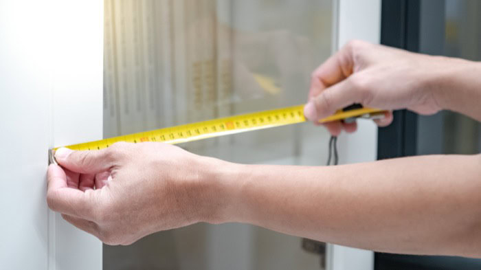 Messung mit einem Maßband an einer Wand für präzise Raumplanung.